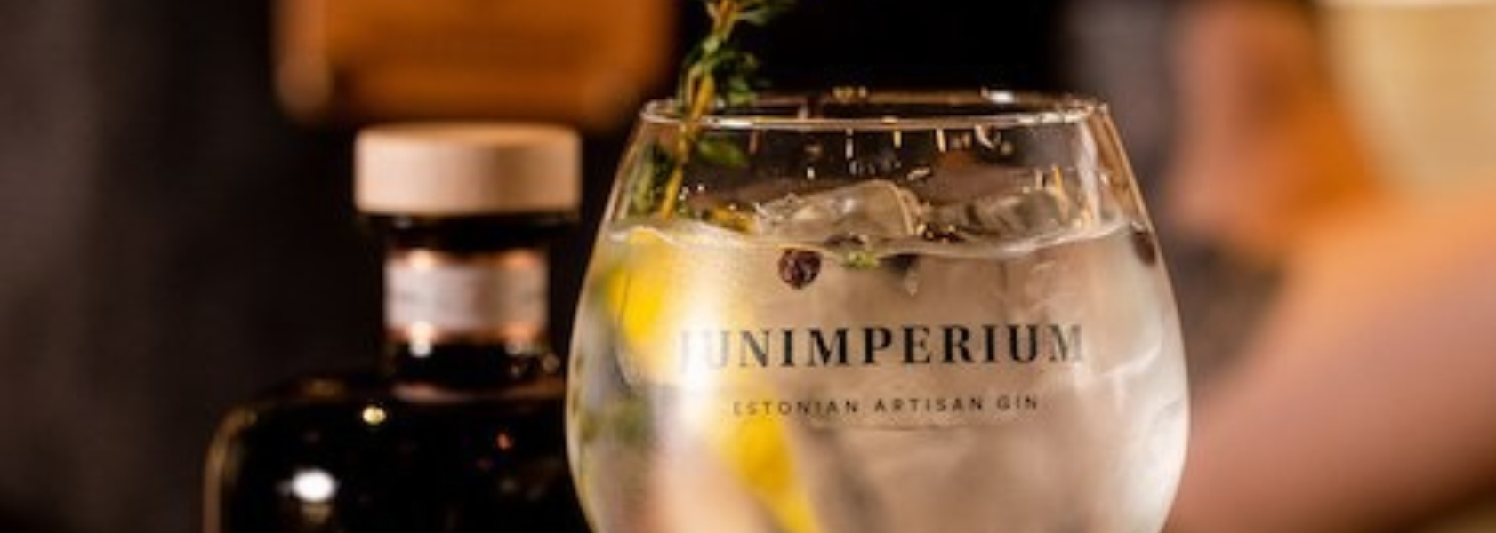 Junimperium Estonian craft gin on a bar counter with juniper sprigs