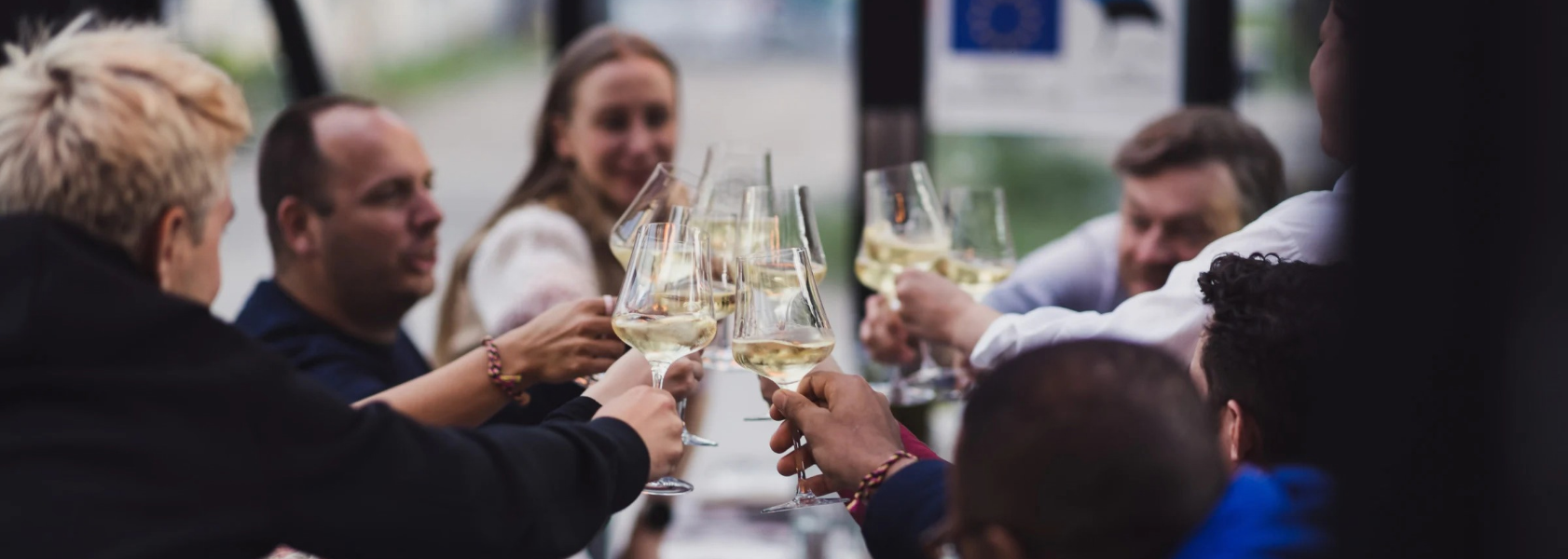 Group raising white wine glasses in a toast at a private dinner
